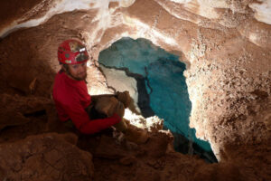 Man sitting above blue lake in cave