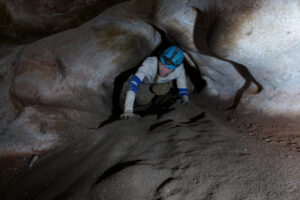 A caver makes his way through one of the many crawls in the cave